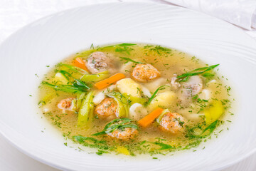 Chicken soup bouillon in a plate with chicken balls and vegetables macro close up