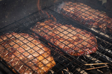 Selective focus of juicy beef steaks grilling on barbecue grid with smoke. High-quality photo