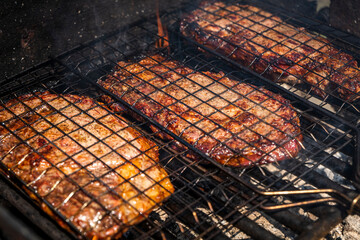 Selective focus of juicy beef steaks grilling on barbecue grid with smoke. High-quality photo