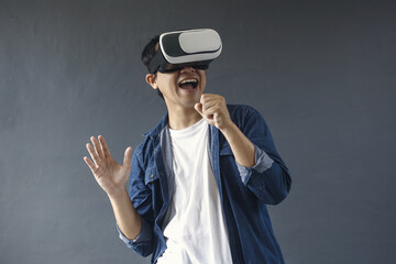 Attractive asian man karaoke using VR glasses is singing a song  againts dark grey background. 