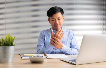 businessman with symptoms numb hands on the desk from hard work
