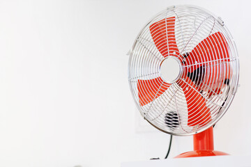 A modern red standing fan against white wall