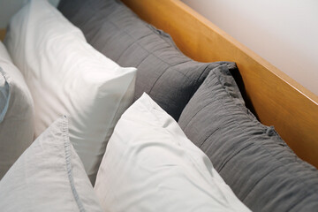 Wooden bed with soft fabric pillows in a modern room.
