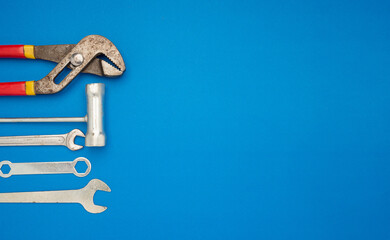 Work tools over a blue background. Pliers, screwdriver, and spanner