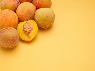 Pile of fresh peaches fruit over a yellow background