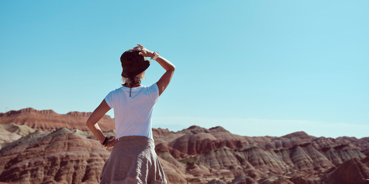 rear view of female asian tourist looking at the yardang landforms in national park