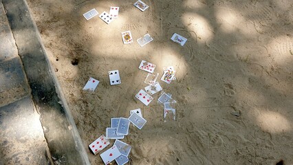 A random, disorganized selection of playing cards thrown onto the floor of sandy beach