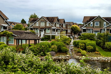 Fototapeta na wymiar Residential District in Richmond City, a village of townhouses , green grass bushes and trees in the territory of residential complex, blue sky, Vanсouver, British Columbia 