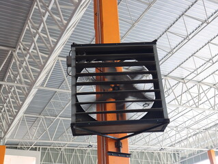 Industrial fans are installed on orange poles in industrial plants.