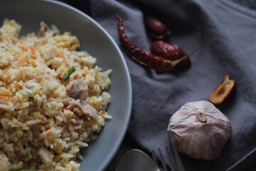 Pork fried rice is a common street food in Thailand. Served on a black wooden table.