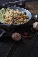 Pork fried rice is a common street food in Thailand. Served on a black wooden table.