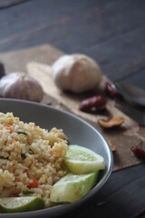 Pork fried rice is a common street food in Thailand. Served on a black wooden table.