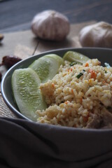 Pork fried rice is a common street food in Thailand. Served on a black wooden table.