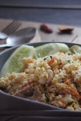 Pork fried rice is a common street food in Thailand. Served on a black wooden table.