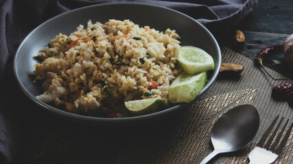 Pork fried rice is a common street food in Thailand. Served on a black wooden table.