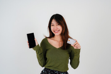 Naklejka premium Image of a beautiful young pretty woman posing isolated over white wall background using mobile phone holding credit card.