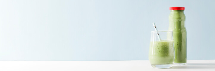 healthy green smoothie in glass, bottle with straw on blue background. Vegetarian healthy lifestyle concept.refreshing drink. copy space banner