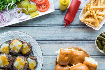 freshly barbecued beef sliders with buns, toppings and french fries.
