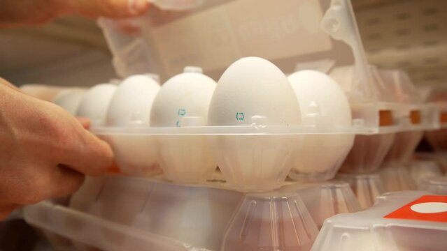 Close-up of a plastic packaging of eggs and two male hands open it to check the eggs integrity and then take it