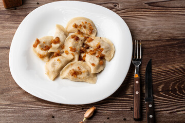 Traditional ukrainian dish vareniki served in a bowl with greaves and sour cream. Close up view of traditional Ukrainian food.
