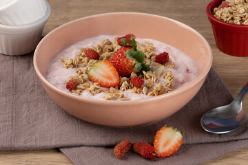 A bowl of delicious strawberry yogurt with granola, strawberry and blackberry. Selective focus.