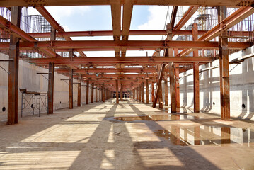 Reinforced steel frame structure under the construction building with steel piles screwed into the ground. Industrial concept.