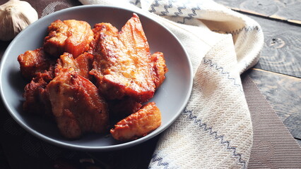 Fried Pork Belly with Fish Sauce Served on a Gray plate on a black wooden floor.