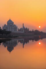 Fototapeta na wymiar Taj Mahal reflected in Yamuna river at sunset in Agra, India