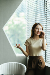 Asian woman in casual clothes is happy and cheerful while communicating with her smartphone and working in a coffee shop.