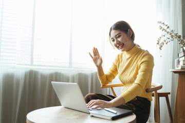 Asian woman having video call on her computer at home. Smiling girl studying online with teacher.