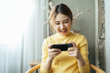 Asian woman excited while playing mobile games, reading good news while surfing the internet world.