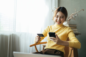 Asian woman in casual clothes is happy and cheerful while communicating with her smartphone and working in a coffee shop.