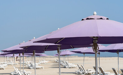 Purple beach umbrellas. Blue sky. Relaxing context. Summer holidays at the sea. General contest and location