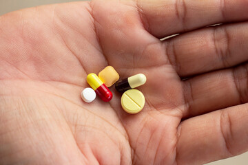 Closeup medicine pills and capsule of various sizes in the hands of the patient.