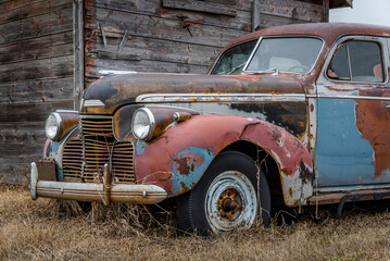 Obraz na płótnie Canvas An abandoned multicoloured sedan on the prairies in Saskatchewan