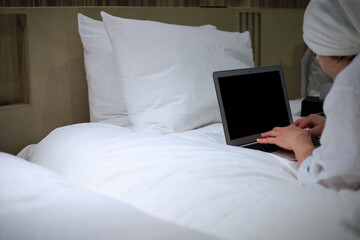 ホテルのベッドの上ででノートパソコンを使用している女性
