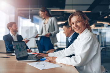 Obraz premium confident smiling businesswoman sitting at the office with group of colleagues, on background.