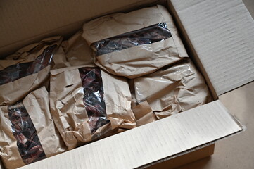 Open rectangular box. Brown paper bags with a transparent window lie inside.