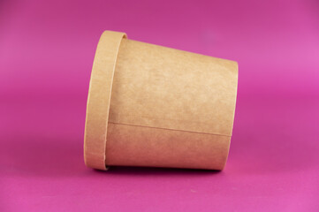 Food to take away. Closed cylindrical paper container with lid opposite colored background. Brown food container for soup, ice cream, noodles or other food.