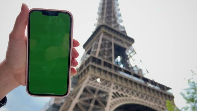 Girl looks at the phone lifting it up with chromate blonde natural hair developing green screen flipping her finger against the background of a beige building. High quality 4k footage