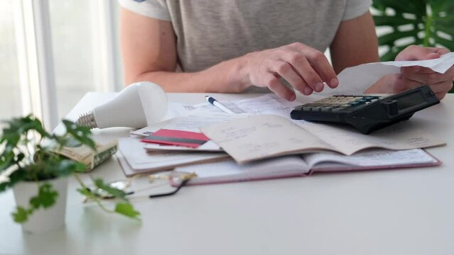 A man counts a bill on a calculator on the table. Payment of utility services. Saving energy and money concept.