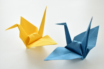 Blue and yellow origami paper cranes on white background.