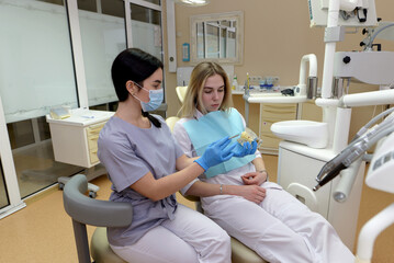  dentist showing a model of an artificial jaw to a patient