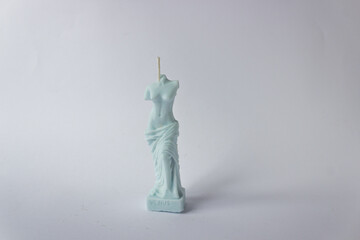 Single handmade candle of natural soy wax in the form of a Venus female torso in blue pastel color. White background.