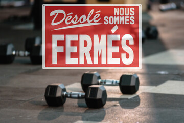 in French inscription sorry we are closed. the closure of the gym during the lockdown. dumbbells on...
