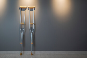 Crutches at wall.Success concept with crutches in the shadow of ladder. Insurance for heath care concept. Pair Of Two Crutches Leaning On White Wall.