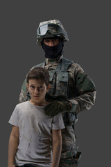 Soldier protecting little kid. Special force army man and young boy against gray background.