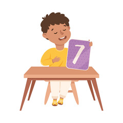 Little Boy with Number Seven Sitting at Desk Showing Card with Numeral Vector Illustration