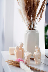 Body candles on a dressing table with spikelets of dried flowers on a light background.