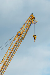 Bright yellow Industrial construction crane against a cloudy sky. Vertical format.
